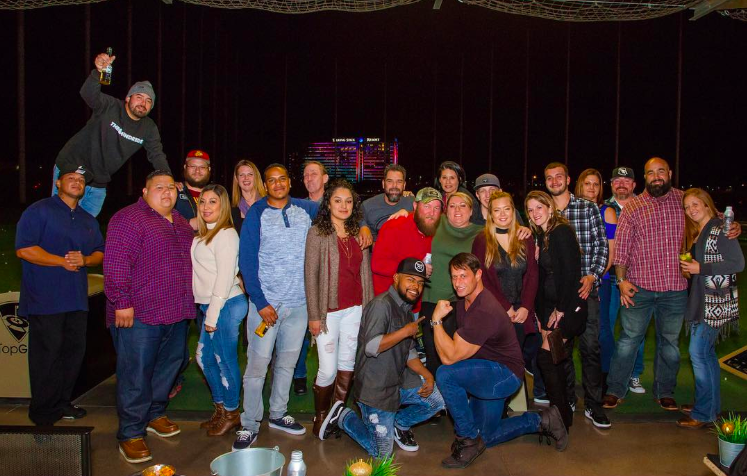 Group of men and women posing for a picture in front of a dark background